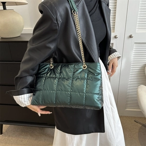 Détail d'un sac cabas matelassé vert foncé avec des lanières en chaîne dorée et tissu doux