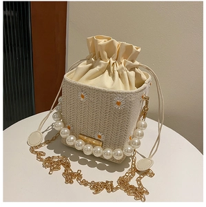 Detail of straw bucket bag with daisy embroidery, pearl handle and gold chain strap