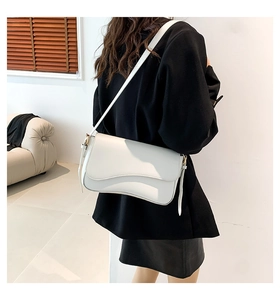 Detail of white leather shoulder bag with unique wavy flap design and gold hardware