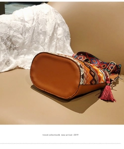 Macro detail of Bohemian bucket bag showing ethnic embroidery and leather base texture