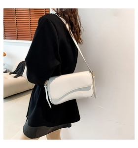 Detail of cream flap shoulder bag with unique wavy edge and adjustable gold hardware