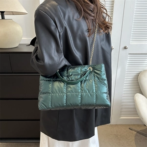 Sac fourre-tout matelassé vert foncé avec bandoulière chaîne dorée porté par un mannequin