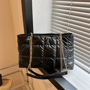 Détail du sac fourre-tout matelassé noir avec chaîne dorée et texture nylon brillante