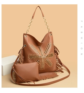 Detail of brown leather bucket bag set with gold rivets, fringe trim and chain strap