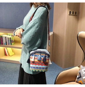 Close-up of ethnic woven bucket bag with colorful tassel details and wide strap