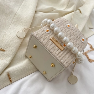 Straw bucket bag with daisy embroidery, pearl handle, and metal chain shoulder strap