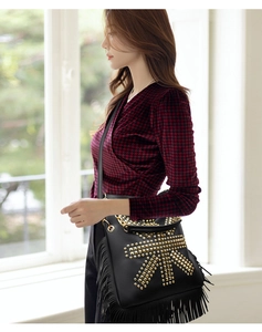 Detail of black leather bag with gold punk studs and long fringe tassels on the bottom