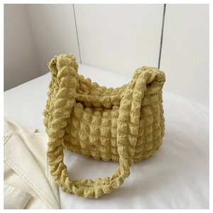 Close-up of ginger yellow bubble texture pleated shoulder bag with soft elastic fabric