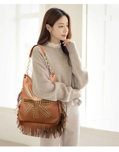 Detail of bohemian brown tassel shoulder bag with golden punk rivets and chain strap