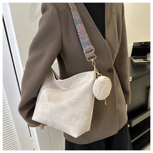 Detail of beige hobo bag featuring ethnic patterned wide strap and mini coin purse charm