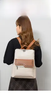 Detailed back view of a minimalist beige and brown backpack with rivet accents