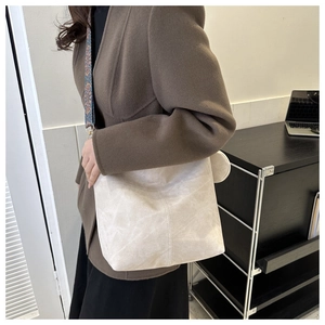 Detail of minimalist cream bucket bag featuring a wide retro geometric woven strap