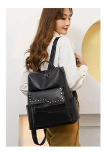 Side view of black soft leather backpack with silver rivets and multi-pocket design