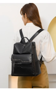 Detail showing vintage black soft leather backpack with stylish rivet accents on model