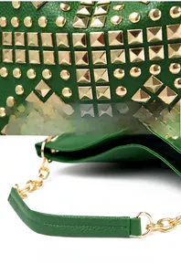 Detailed close-up of golden rivets and metal chain handle on green faux leather shoulder bag