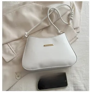 Detail of minimalist beige PU leather crossbody bag with gold metal trim and knotted strap