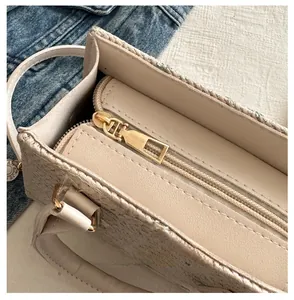 Détail macro de la fermeture éclair dorée lisse sur le sac à main de couleur crème