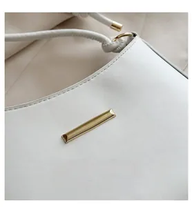Detailed close-up of white leather handbag with elegant gold metal hardware and fine stitching