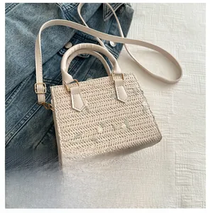 Détail de broderie florale sur un mini sac en paille avec poignée et bandoulière