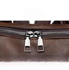 Detail of dark brown lychee texture leather backpack with smooth silver metal zippers