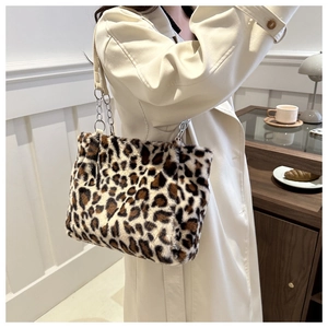 Close-up of leopard print plush tote bag with silver chain strap on a wooden side table