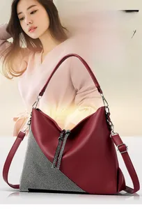 Close-up of wine red lychee leather handbag with rhinestone triangle detail and silver zip