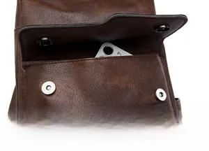 Close-up of vintage brown leather backpack with magnetic snaps and front phone pocket