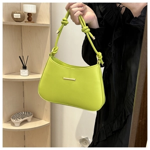 Detail of lime green leather shoulder bag featuring knotted strap and gold hardware