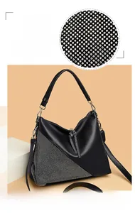 Detail of black leather hobo bag featuring asymmetric rhinestone inlay and crystal tassel