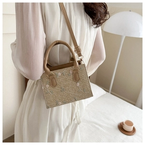 Détail de broderies florales sur un sac à main en paille tressée avec bandoulière