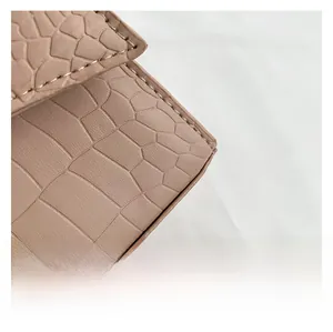 Gros plan du motif crocodile sur le sac à main rose poudré avec coutures précises