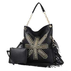 Detail of black pebbled faux leather tote with golden studs and long bohemian tassels