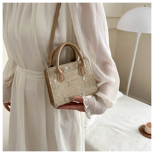 Détail de la broderie fleurie rose sur un sac à main en paille tressée avec anse
