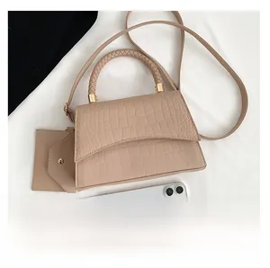 Détail d'un sac à main marron clair à motif crocodile avec mini pochette et poignée tissée