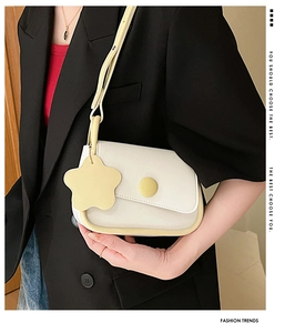 Piccola borsa bianca minimalista con profili gialli e ciondolo a stella su blazer nero