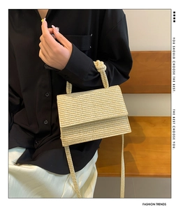 Detail of woven straw handbag featuring fine horizontal texture and knotted handle design