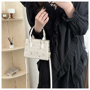 Détail d'un sac cabas tressé blanc avec broderie florale verte et anse en cuir