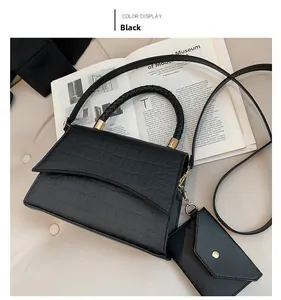 Détail d'un sac noir à motif crocodile avec poignée tressée et accents dorés sur un livre