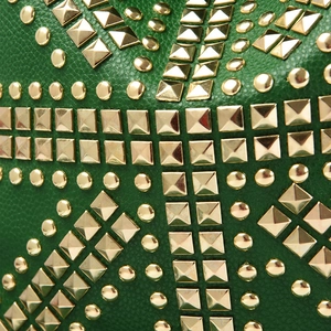 Detail of green litchi leather bag featuring golden studs and punk style rivets