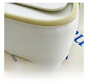 Dettaglio delle cuciture precise e del bordo verde chiaro su una borsa bianca