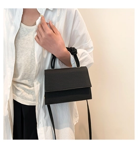 Detail of black woven texture crossbody bag with unique braided rope handle on model