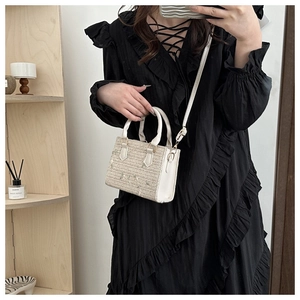 Détail du tissage en paille et de la poignée en cuir blanc sur le petit sac carré