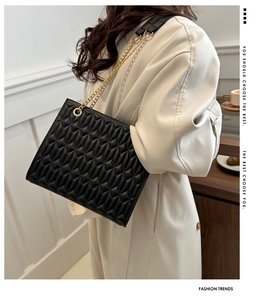 Black quilted crossbody bag with gold chain strap shown on model for a stylish look