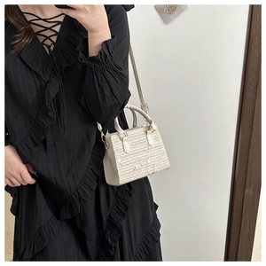Détail du sac à main en paille tissée avec poignée en cuir sur robe noire élégante