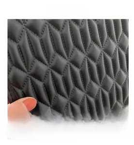 Close-up of black quilted leather texture with geometric diamond stitching on handbag