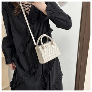 Détail du sac à main en paille tressée beige avec poignées en cuir et bandoulière