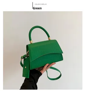 Détail du sac à main vert croco avec poignée tressée et fermoir métallique doré