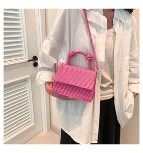 Detail of bright pink woven texture crossbody bag with knot handle and shoulder strap