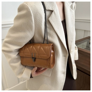 Gros plan du sac matelassé caramel avec fermoir en métal et bandoulière sur un mannequin