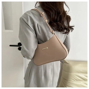 Minimalist beige moon-shaped underarm bag with knot strap shown on a model